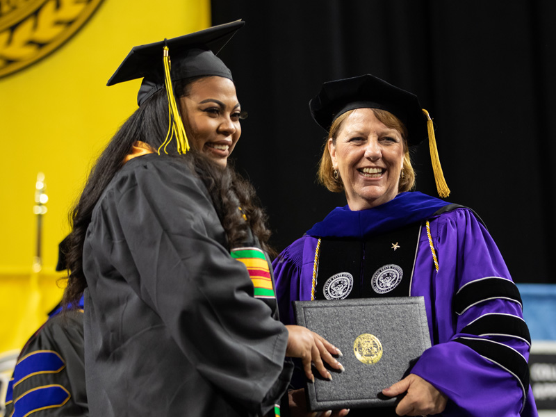 Shirley Lefever handing a diploma to a student at commencement